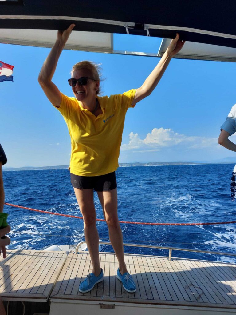 Skipperin Sonja steuert ein Segelboot im Sailwithus-T-Shirt