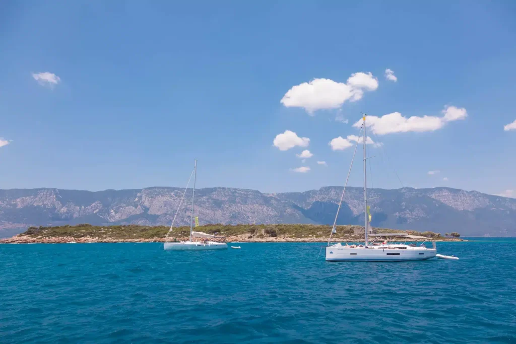 Zwei Segelboote auf dem klaren blauen Wasser vor der malerischen Küste Südfrankreichs.
